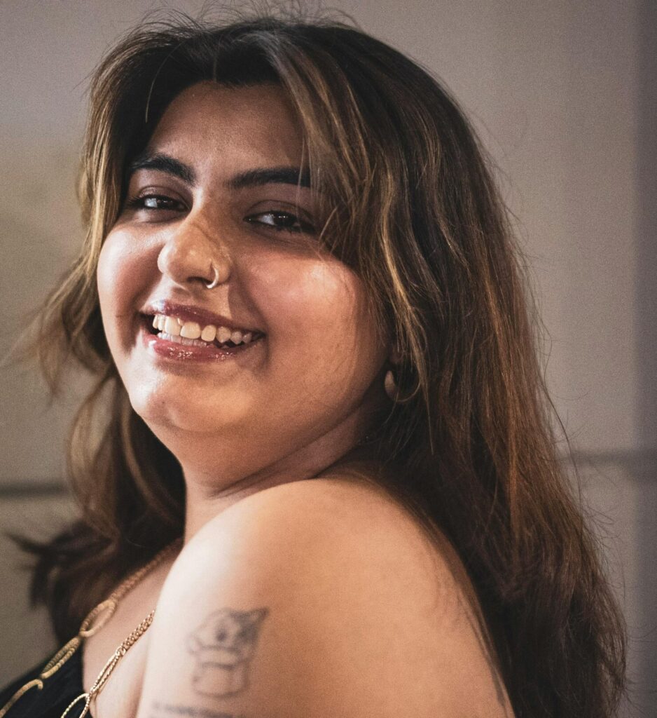 A young woman with a tattoo smiles in a modern vintage style in Milan, Italy.